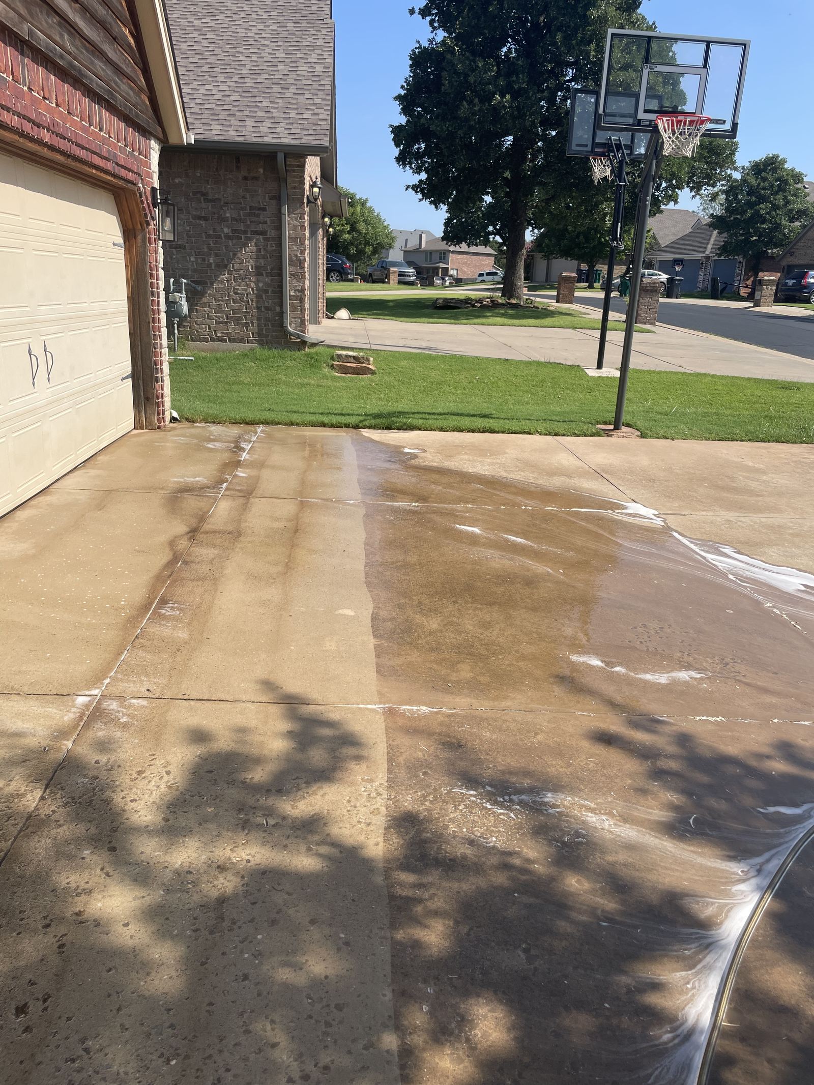 Pressure washing in progress, cutting a clean line through a dirty driveway